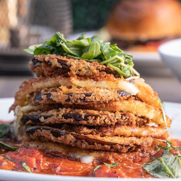 Stacked fried eggplant parmesan with marinara sauce and fresh greens at Wildfire Public House.