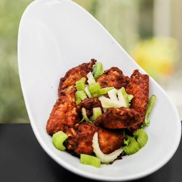 Wildfire Public House's gastropub chicken wings, coated in a rich sauce and garnished with fresh celery.