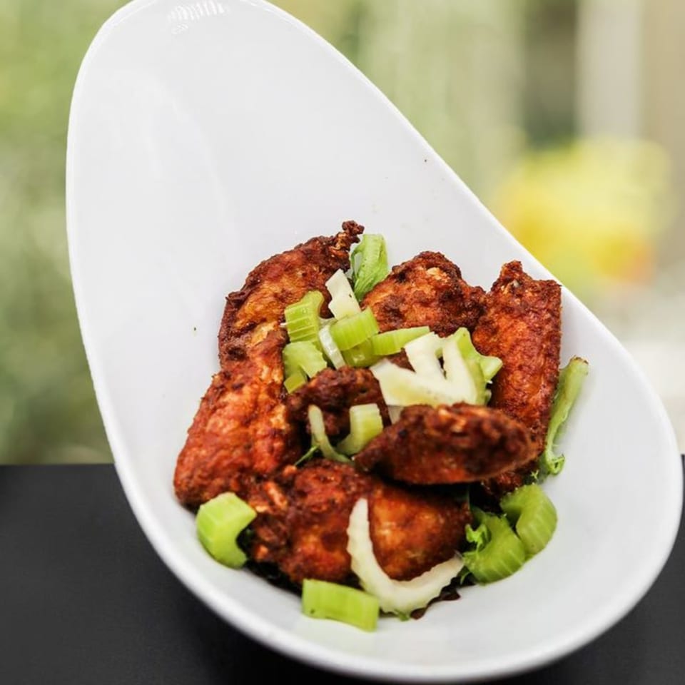 Wildfire Public House's gastropub chicken wings, coated in a rich sauce and garnished with fresh celery.