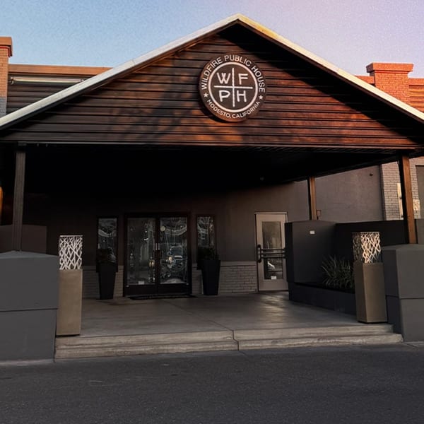 Exterior of Wildfire Public House, a gastropub, with its logo on a dark wood facade and glass doors.