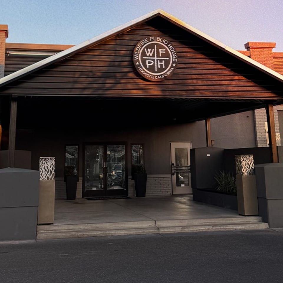 Exterior of Wildfire Public House, a gastropub, with its logo on a dark wood facade and glass doors.